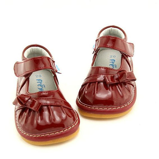 Red Dollhouse Darlings Kids Mary Janes. Girls' vintage-style barefoot feel shoes. Dollhouse Darlings with bows, removable squeakers, genuine leather, and cushioned comfort. Perfect for all adventures.