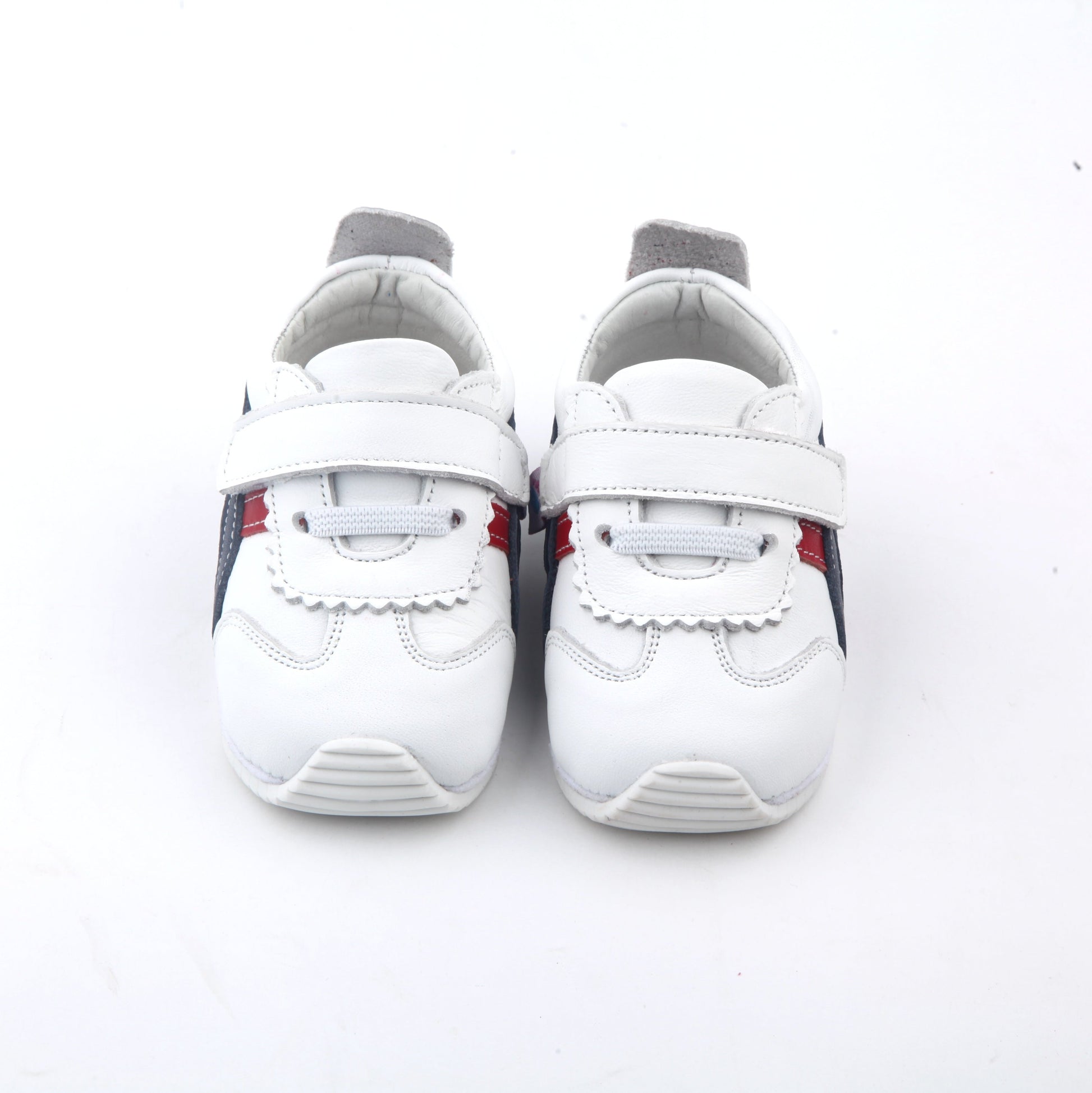 white kids sneakers with blue and red side stripes and velcro straps