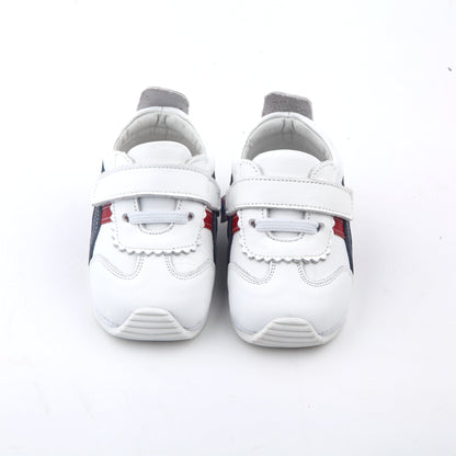 white kids sneakers with blue and red side stripes and velcro straps